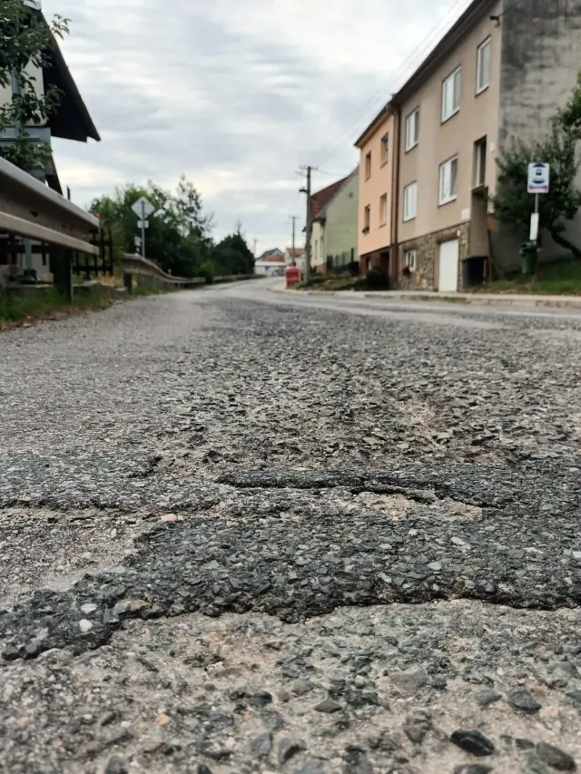 Rozbitý povrch vozovky v ulici Hlavní
